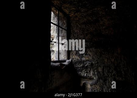 window in the dark in an old abandoned stone building Stock Photo