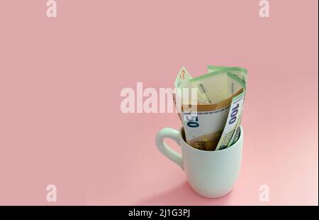 Euro banknotes in a coffee cup on a pink background. Business, financial, exchange Stock Photo
