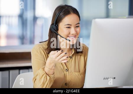 We never keep our customers waiting on the line. Shot of a young businesswoman using a computer while working in a call centre. Stock Photo