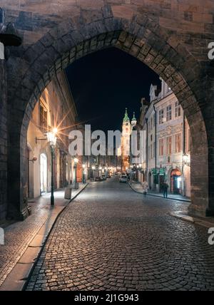 Prague, Czechia - 02.17.2022: View through Mala Strana Tower Bridge arch in the dark night on the Charles Bridge. Center without people. Beautiful Stock Photo