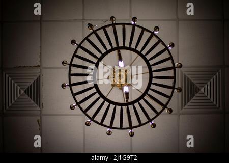 Round chandelier on ceiling. Lamps are shining. Old copper chandelier. Light in great hall. Stock Photo