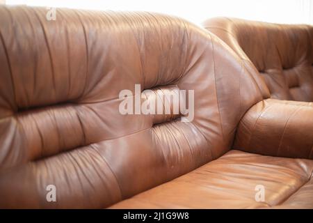 Leather sofa. Furniture for relaxation. Sofa is brown. Old bed. Seating for guests. Stock Photo