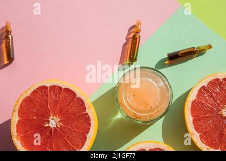 Ampules with vitamin C injection and orange fruit slices on color background Stock Photo