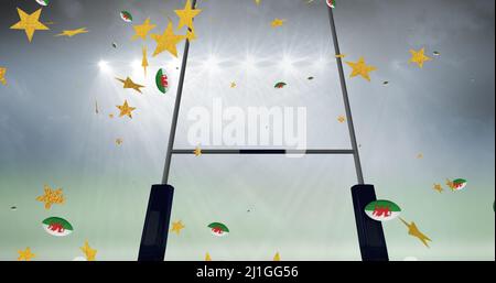 Image of stars over rugby balls coloured with wales flag falling at stadium Stock Photo