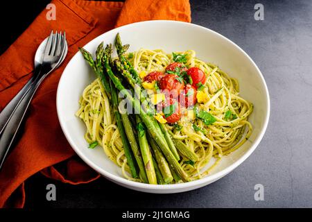 Bowl of Tuscan Linguine Pasta all'Etrusca with Asparagus: Overhead view of noodles topped with roasted cherry tomatoes, asparagus, and egg yolk Stock Photo