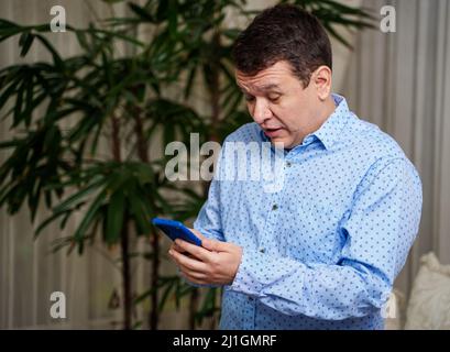 Surprised young executive looking at news or information on his smartphone Stock Photo