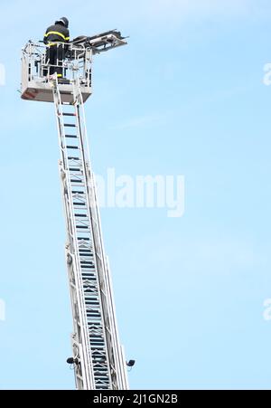 brave firefighter who saves the injured person using the truck with the ladder truck during an emergency and sky on background Stock Photo