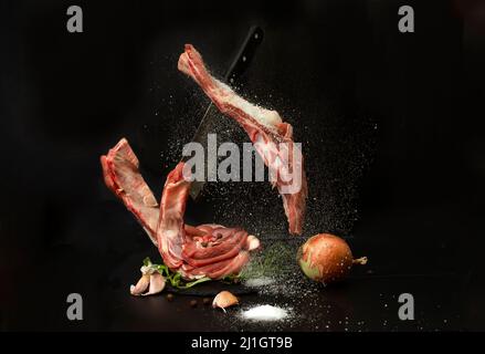 levitating cow ribs being seasoned with salt, on black background Stock Photo