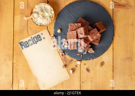 recipe written on a empty vintage paper page next to a pile of  brownies Stock Photo