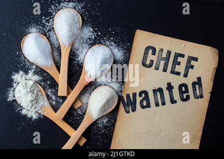 Chef wanted, written on vintage yellowed paper, next to 5 bamboo wooden teaspoons full of salt, sugar flour and  semolina Stock Photo