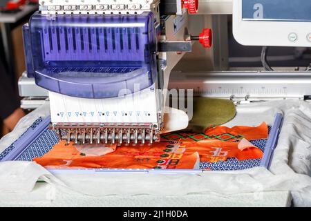 Modern electronic professional embroidery machine for embroidery with multi-colored threads on various fabrics. Selective focus. Copy space. Stock Photo