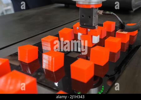 Pick and place robotic arm manipulator moving red toy blocks at robot exhibition Stock Photo