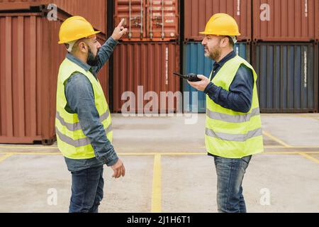 Industrial engineer people working at container cargo logistics terminal port - Focus on right man face Stock Photo