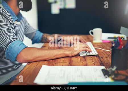 Connected hands are productive hands. Cropped shot of a businessman using a computer at his desk in a modern office. Stock Photo