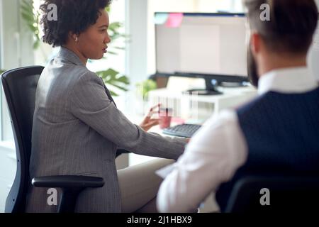 A young female employee is working at the desk in a working atmosphere in the office with her male colleague. Employees, job, office Stock Photo