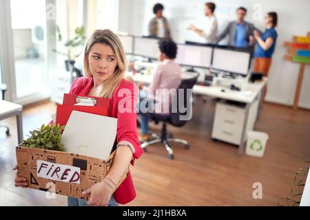 A young female clerk in tears leaves the office after she is being fired from the job she likes. Employees, job, office Stock Photo