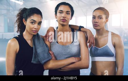 Together we stand undefeated. Portrait of three young sportswomen standing and posing in the gym. Stock Photo