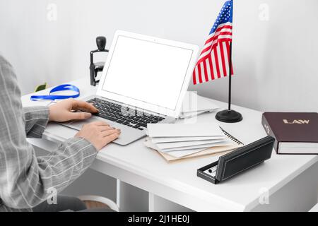 Woman using laptop on table with USA flag near light wall Stock Photo