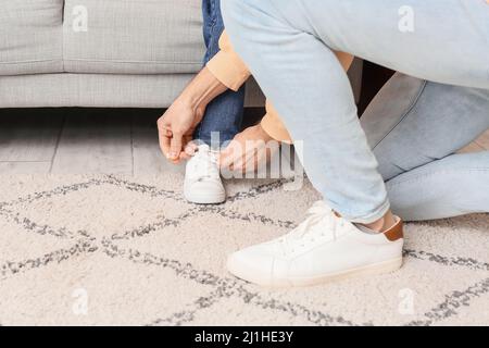Father tying laces on shoe of his little daughter st home Stock Photo