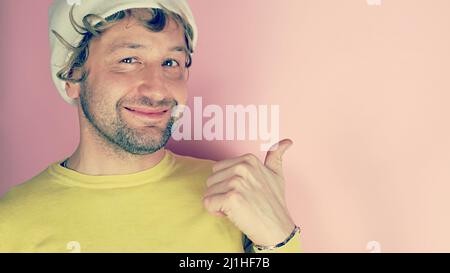 Close-up portrait of lovely cheerful confident unshaved young man showing thumb copy space isolated over pink pastel color background Stock Photo
