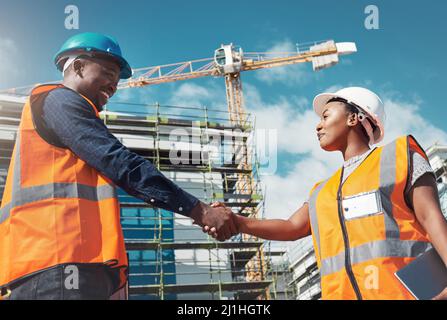 The perfect blend of construction skills and collaborative skills. Shot of two builders shaking hands at a construction site. Stock Photo