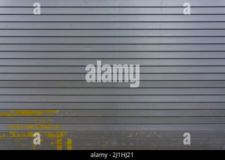 Metal door gray in color with yellow paint splattered on lower end. Stock Photo