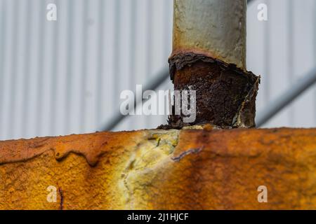 Decaying rusted pole at the base of safety railing on top of rust covered step. Stock Photo
