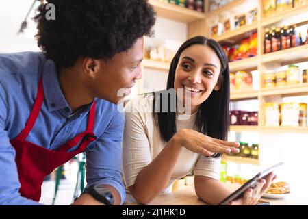 Smiling young female caucasian owner discussing with african american employee at coffee shop. unaltered, cafe culture, people and occupation concept. Stock Photo