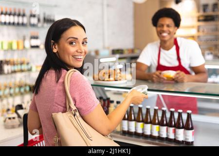 Portrait of smiling caucasian female customer with african american male owner at coffee shop. unaltered, cafe culture, people, occupation and lifesty Stock Photo