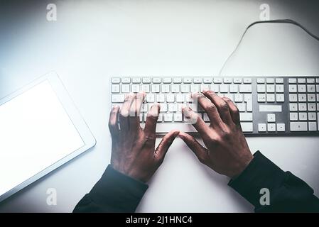 Fastest fingers on the web. High angle shot of an unrecognizable man typing on a keyboard while working late in the office. Stock Photo