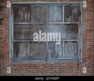 Old weathered closed wood shutters on aged red brick background Stock Photo