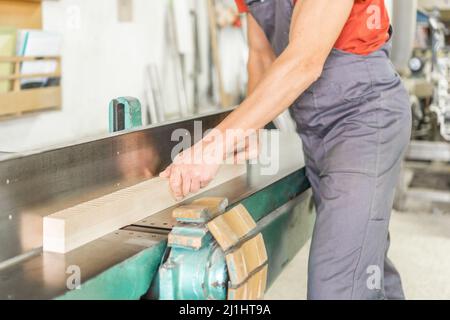 Unrecognizable carpenter trimming wooden plank in workshop Stock Photo