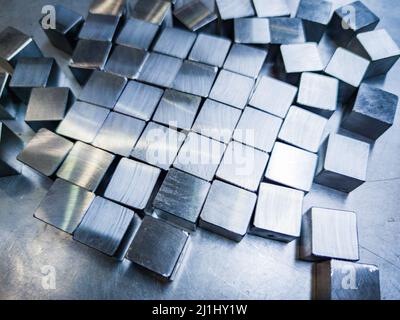 pile of small machined shiny steel cubes on metal surface Stock Photo