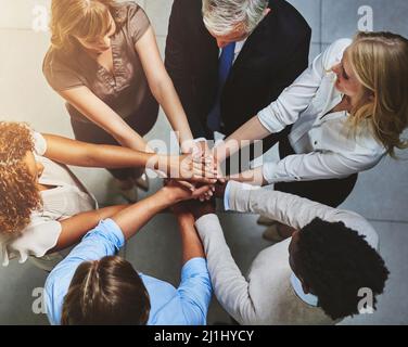 Get involved, get it done. High angle shot of a group of colleagues joining their hands in solidarity. Stock Photo