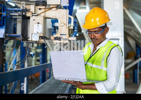 industrial worker busy using laptop at workplace - concept of technology, safety and maintenance engineer Stock Photo