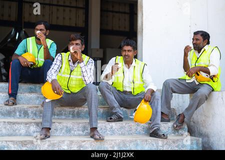 Group of Industrial workers having tea or coffee during break - concept of relaxation, coworkers and blue collar jobs Stock Photo
