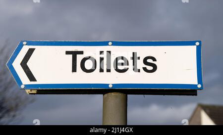 Blue and white toilets direction sign against a blue sky Stock Photo