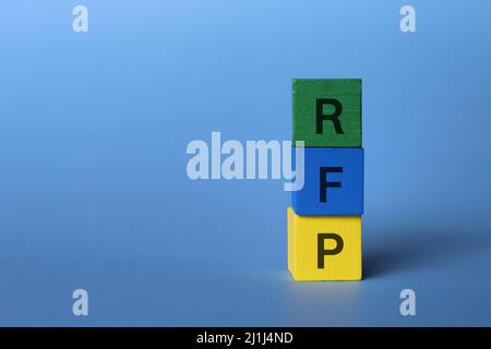 Wooden cubes with text RFP acronym for request for proposal on blue background with copy space. Stock Photo