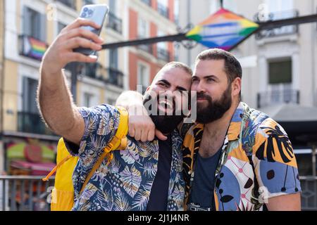Two gay men on vacation taking a photo together with mobile phone during a sightseeing tour in a city. Lgbt couple traveling. Stock Photo