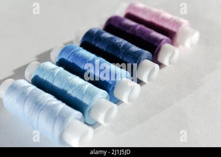 The bobbins with the light blue, dark blue and violet threads. A set of sewing thread reels on a white background. Several turns of thread of differen Stock Photo