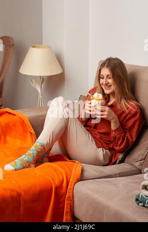 Woman rests on the sofa with a mug fox Stock Photo