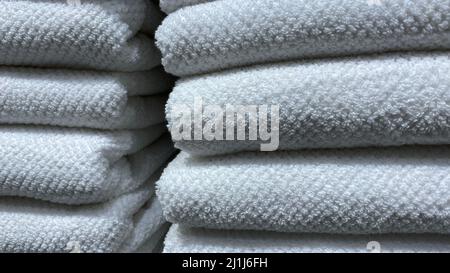 Towels. A stack of folded white cotton terry towels in close-up. Fabric Texture Stock Photo