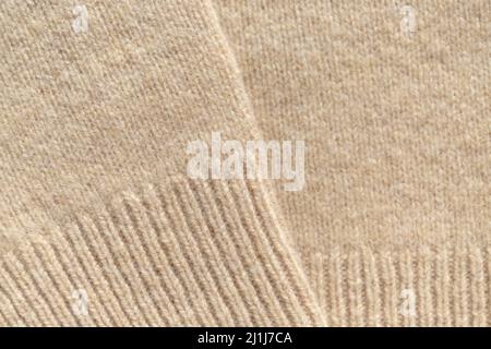 Knitted sweaters of beige warm pastel color with vertical knitting, the texture is clearly visible. Stock Photo