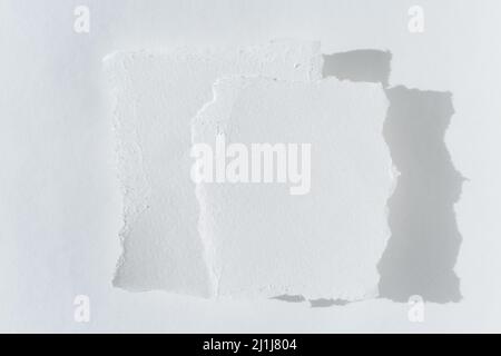 A white torn note, scraps of paper. Two pieces of torn white paper on a light background. Stock Photo