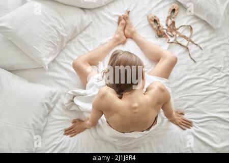 Woman wrapped in blanket posing on light bed Stock Photo