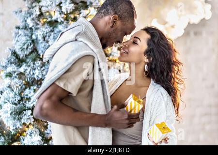 A happy couple of mulattoes exchange gifts with each other. Celebrating joint family events Stock Photo