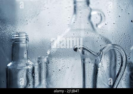 Carafe for water. Glass transparent bottles in water drops. Glass dishes. Stock Photo