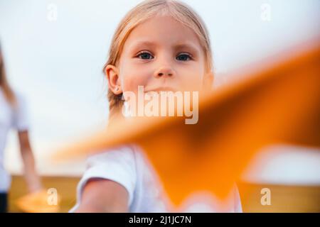 Cute child girl running and playing toy paper airplane in the field in summer day Stock Photo