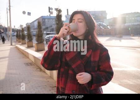 Woman drinking coffee in the sun, outdoor in sunlight light, enjoying her morning coffee.