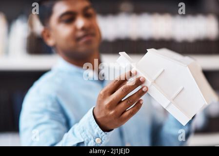 Say hello to your new home. Shot of a young architect designing a building model in a modern office. Stock Photo